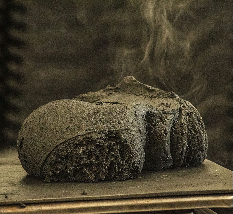 Detalle técnico de concreto plástico de EcoAlquimia recién fundido, mostrando la mezcla homogénea de polímeros reciclados y relleno mineral antes de su solidificación monolítica.